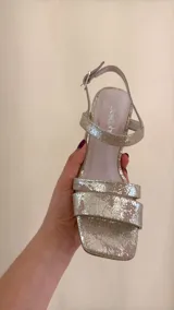 Sandalia dorada de cuero con doble tira delantera, horma cuadrada y ajuste con hebilla.