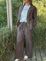 Blazer azul marino con rayas verticales blancas, confeccionado en lino italiano. Tiene botones de coco, solapas clásicas y bolsillos delanteros.