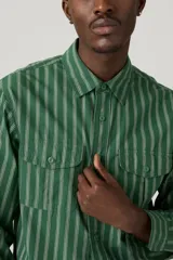 Camisa verde con rayas verticales blancas, de manga larga y corte recto.