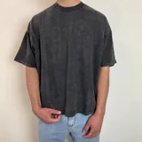Remera negra con efecto gastado y estampado abstracto en la espalda. Corte boxy y mangas cortas.