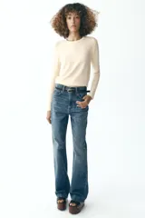 Sweater negro de punto liso con cuello redondo y mangas largas con botones dorados en los puños.