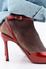 Sandalia de tacón fino color rojo, con tira delantera ancha, pulsera de tobillo con hebilla metálica y punta metálica.