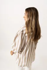 Camisa a rayas verticales color beige y blanco, de corte holgado, con cuello camisero y mangas largas abullonadas con puños abotonados.