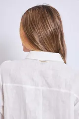 Vestido camisero corto color crudo, de lino, con cuello camisero, mangas largas y cierre frontal con botones. Presenta apliques de encaje en cuello y hombros.