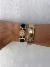 Pulsera con banda de terciopelo gris y apliques dorados con forma de moneda antigua.
