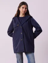 Gabardina impermeable color beige, marca Weatherproof, con abertura central con botones, bolsillos delanteros y capucha desmontable.