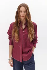 Camisa negra de manga larga con cuello clásico y cierre frontal con botones. Presenta costuras decorativas en color blanco.