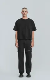 Pantalón cargo negro de corte recto con bolsillos laterales con solapa y etiqueta con texto en la pierna derecha.