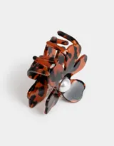 Broche para el pelo con forma de flor con estampado carey y detalle de perla en el centro.