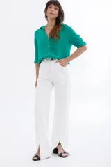 Pantalón jean blanco de corte wide leg con aberturas en el ruedo.