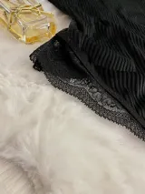 Body negro de terciopelo con mangas largas de tul y detalles de encaje en puños y parte inferior.