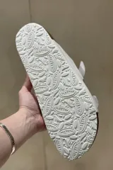 Sandalias blancas de cuero con doble tira y hebillas metálicas ajustables. Suela anatómica de corcho y goma.