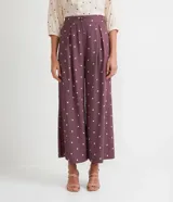 Pantalón pantacourt de viscosa color lila con estampado de pequeños cuadrados blancos. Tiene pinzas delanteras, bolsillos laterales y cierre con botones.