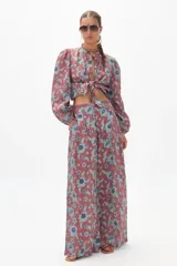 Conjunto de pantalón y blusa de lino con estampado floral en tonos terracota y azul. La blusa es de manga larga con cuello mao y se ata en la parte delantera. El pantalón es culotte de tiro alto con bolsillos laterales y cierre frontal escondido.