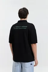 Polo azul marino con textura y corte oversize. Presenta un logo estampado en el pecho y mangas cortas.