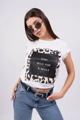 Remera blanca de algodón con estampa rectangular con borde de animal print y texto 'Stay wild for a while'.
