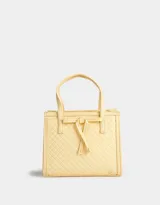 Cartera mini city color amarillo claro, de cuerina trenzada, con doble asa corta de mano, correa regulable desmontable, cierre superior y moño decorativo.