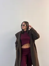 Conjunto de dos piezas color beige, compuesto por un top corto de mangas largas y un pantalón de corte recto.