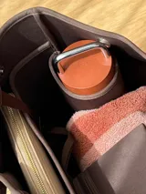 Bolso negro tipo tote de neopreno con bolsillo interno de red, sobre haciendo juego y gancho para sujetarlo.