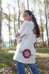 Maxi cardigan color crema de lana merino con bordado de flores rojas y azules.