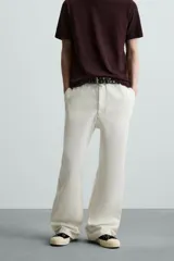 Pantalón negro de algodón con corte relajado y pierna ancha (flare fit). Presenta cierre frontal con botón y cremallera, bolsillos delanteros y bolsillos traseros de plastrón.