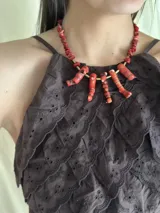 Collar corto con cuentas de coral rojo, bastones de bronce y cadena de acero quirúrgico con cierre de gancho ajustable.