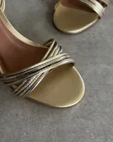 Sandalias doradas con múltiples tiras finas cruzadas sobre el empeine y taco fino de 7 cm.