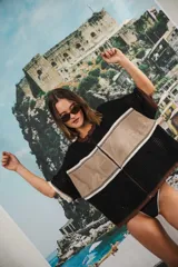 Remera de tejido calado color crudo con rayas horizontales rojas y terminaciones marrones, con cierre frontal y logo bordado.