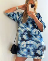 Vestido corto con estampado tie-dye en tonos azules y blancos, de corte recto y mangas cortas.