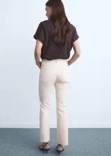 Jeans de tiro medio color beige, con cierre de cremallera y botón, trabillas, cinco bolsillos, bajo deshilachado y estilo flare. Confeccionados en tejido de algodón elástico.