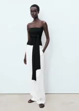 Pantalón de vestir blanco de tiro medio, corte recto y largo, con cierre delantero de botón, gancho y cremallera, detalle de pinzas, dos bolsillos laterales y forro interior.