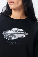 Remera cropped blanca de mangas ranglan con estampa frontal de un auto antiguo y texto "Vintage Gems / retro car club".