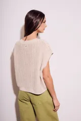 Chaleco de punto calado color beige, con cuello redondo y sisas amplias.