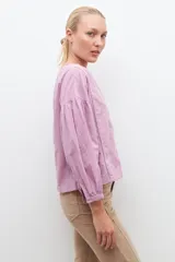 Blusa lila con bordados, de mangas largas abullonadas y cuello en V.