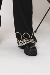Pantalón negro de simil lino, con elástico en la cintura y bordados en la parte inferior.
