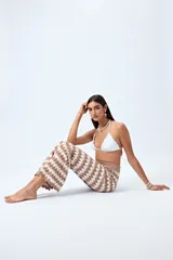 Pantalón tejido con motivo zigzag en tonos beige y blanco, de corte flare y cintura elastizada.