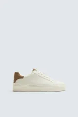 Zapatillas deportivas blancas con detalle de color marrón en el talón y suela con volumen.