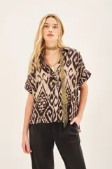 Camisa de corte amplio con estampado ikat en tonos beige y marrón. Tiene cuello camisero, manga corta y botones ocultos.
