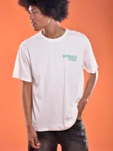 Remera blanca de algodón con cuello redondo y estampado frontal con el texto "Donald Duck" en color verde.