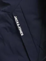 Campera híbrida Jack & Jones color azul marino, ligera y resistente al agua, con capucha, mangas largas con puños elásticos, cierre con cremallera y bolsillos frontales con cierre. Relleno de fibra sintética tipo plumón.