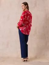 Blusa de gasa roja con estampado floral blanco, cuello a la base con escote en V y mangas 3/4 regulables con presilla y botón.