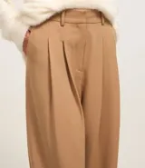Pantalón pantalona de sastrería color beige, con trabillas en la cintura y pliegues delanteros.
