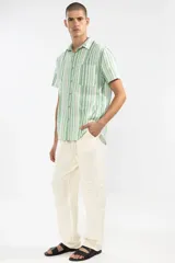 Camisa de manga corta con rayas verticales en tonos verde, blanco y gris. Tiene cuello clásico, bolsillo en el pecho y botones de coco.