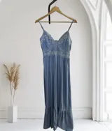 Vestido de jean azul con bordado floral blanco, breteles finos y corte midi.