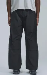 Pantalón técnico negro multipocket con cintura elástica, detalles reflectivos y silueta oversize.
