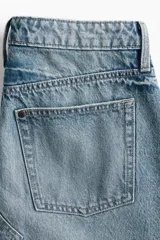 Pollera larga de denim azul, de tiro alto, con cinco bolsillos, cierre de botones y silueta levemente evasé. Presenta nesgas adelante y atrás.