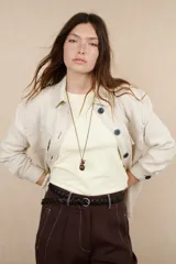 Sobrecamisa color beige de lino con cuello camisero, cierre frontal con botones negros, mangas largas con puños abotonados, dos bolsillos de parche en el pecho y dos bolsillos laterales.