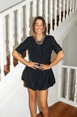 Vestido corto negro con corte en la cintura y falda balloon, de manga corta y cuello redondo.