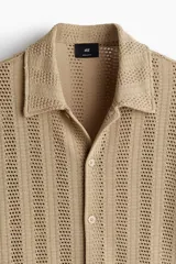 Camisa de manga corta color beige en punto jacquard. Modelo con cuello inglés, tapeta clásica y bajo recto.