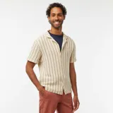 Camisa de manga corta color crema con rayas verticales marrones, cuello cubano y cierre frontal con botones.